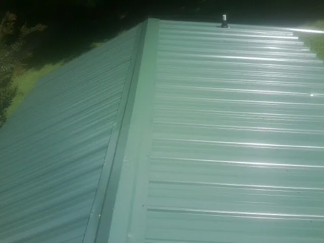 New green metal panels meeting at the ridge of a roof — Flat Roof Repair work by our crew in Olivia