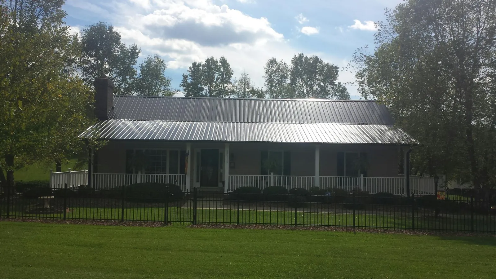 Gray metal roof on a brick ranch with a full width front porch — Gutter Guard Installation work by our crew in Olivia