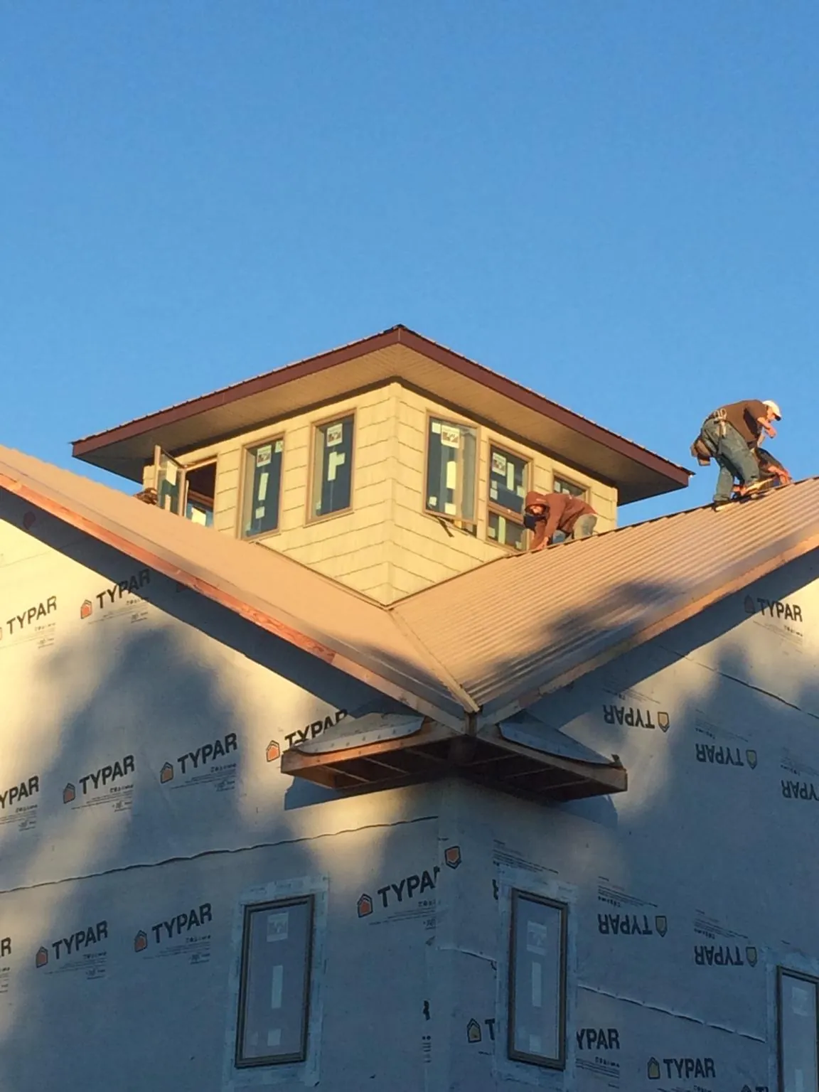 Roofers working around a rooftop cupola on a new metal roof at sunset — Roof Waterproofing in Olivia by Roofing Brothers